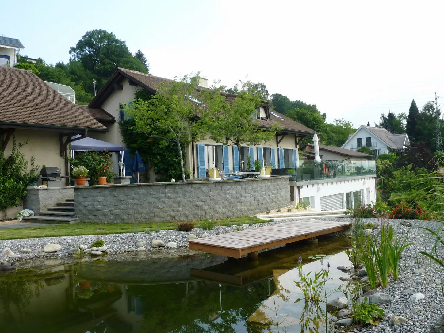Das Haus hinter dem Gartenteich mit kleinem Holzsteg